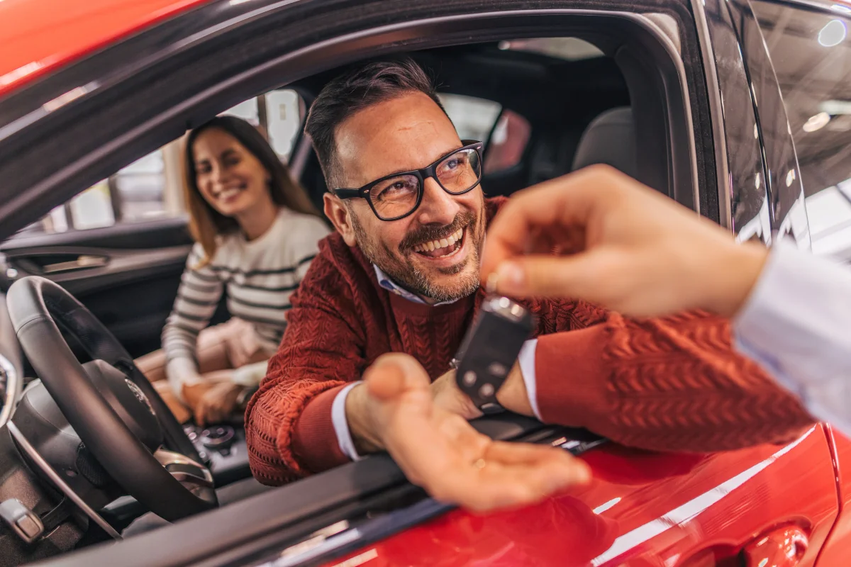 Casal sorrindo dentro do carro novo